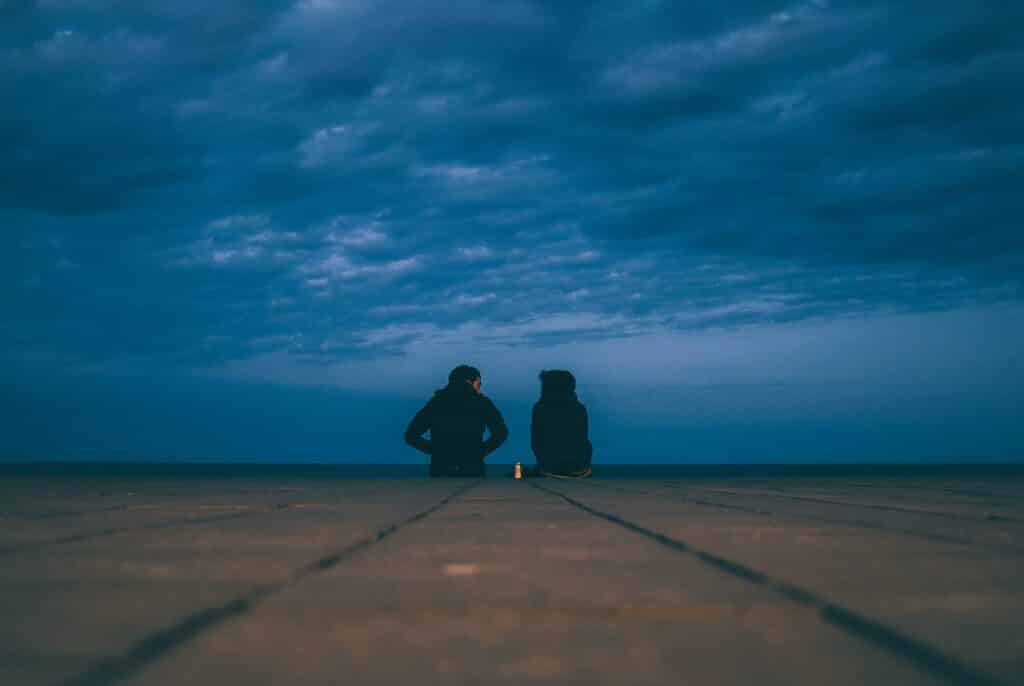 two people talking by the seashore at dusk