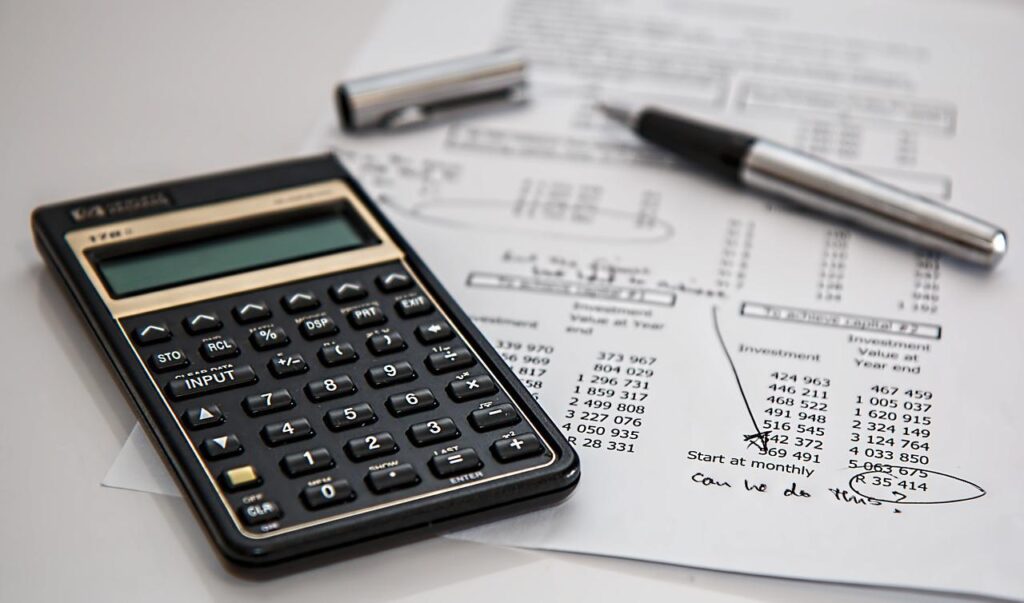 a calculator a pen and a paper containing a breakdown of business expenses - cash vs accrual accounting article