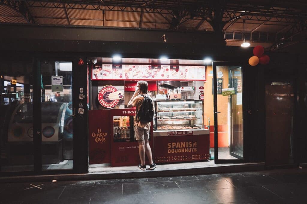 a customer waiting for his order from the spanish doughnut store, as seen from the streets of melbourne, victoria