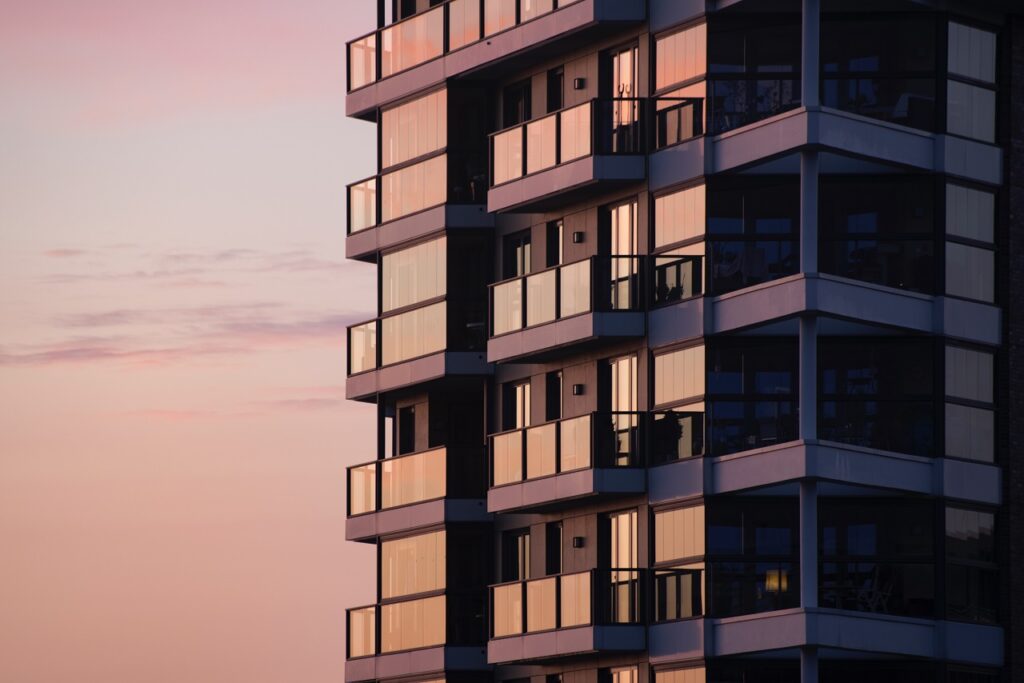sunset light reflects on the glass panels of a high-rise apartment building