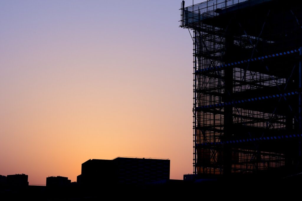 a building under construction with its blue reflectors lighting up as the sun sets