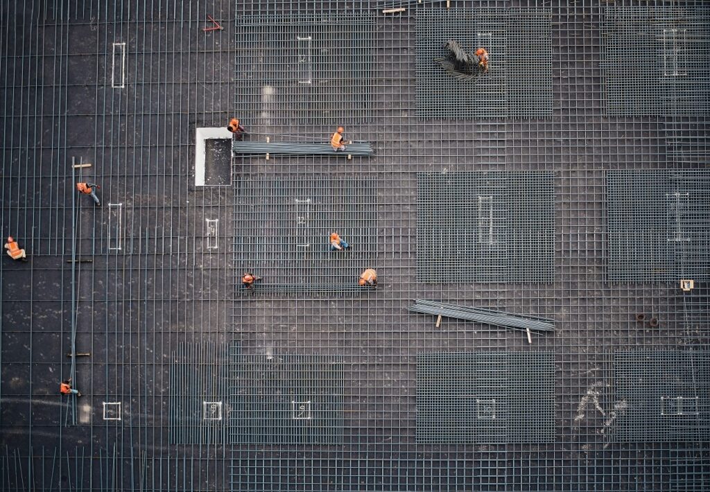 a birds eye view of construction workers laying out the steel bars on the entire floor of a building under construction