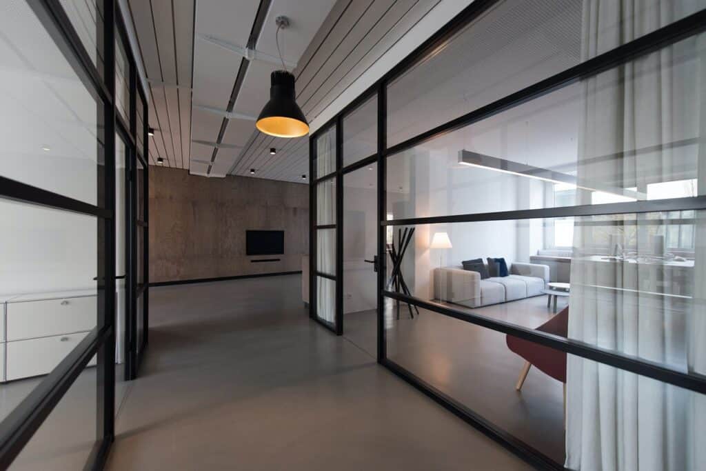 an office corridor lined by glass-panel offices and white curtains