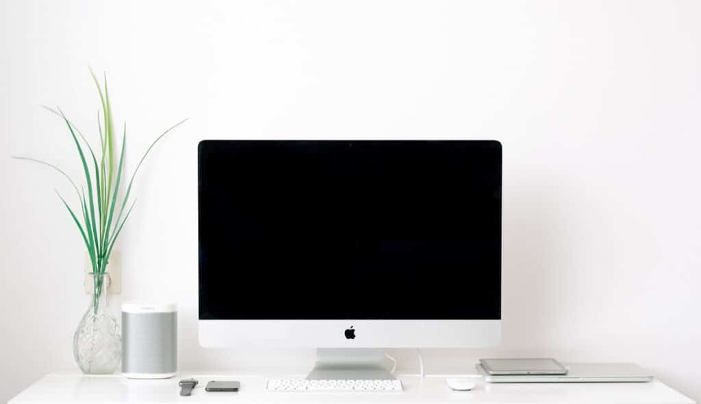 a white work desk with a siver gadgets made by apple