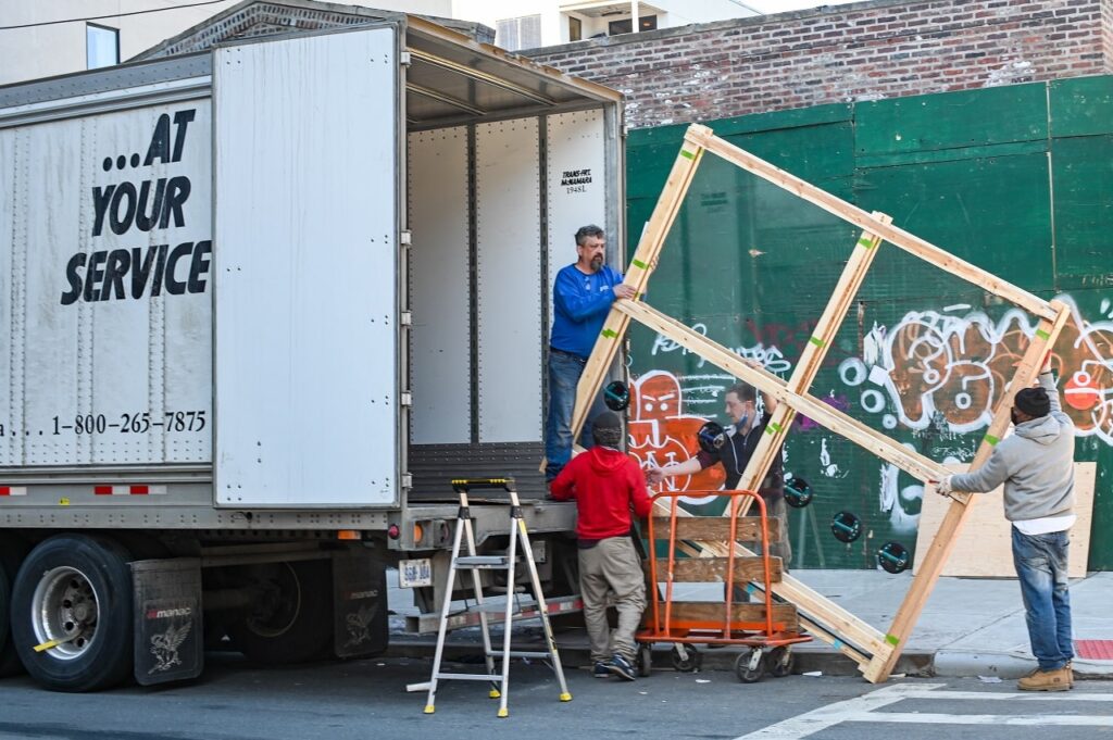 men loading a large wooden frame to a removalist truck