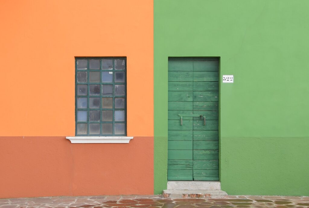 a green, red, and orange building with a wooden front door