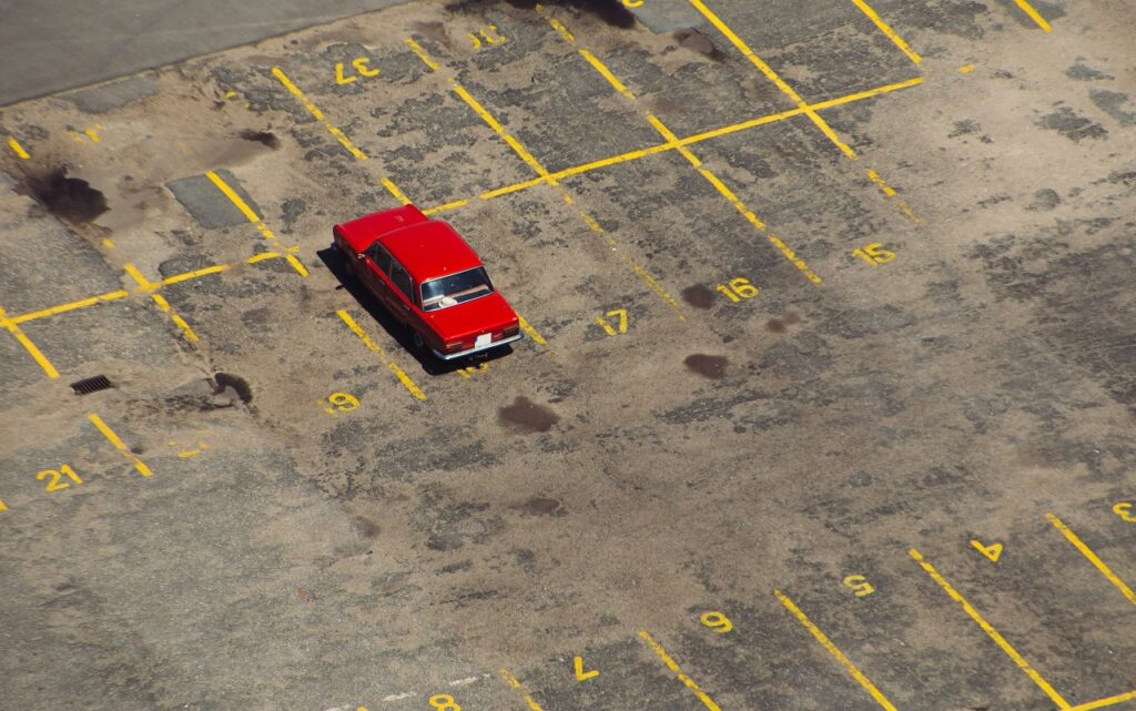 a lone red car in a parking lot
