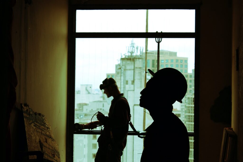 a silhouette of two construction workers working on a wall