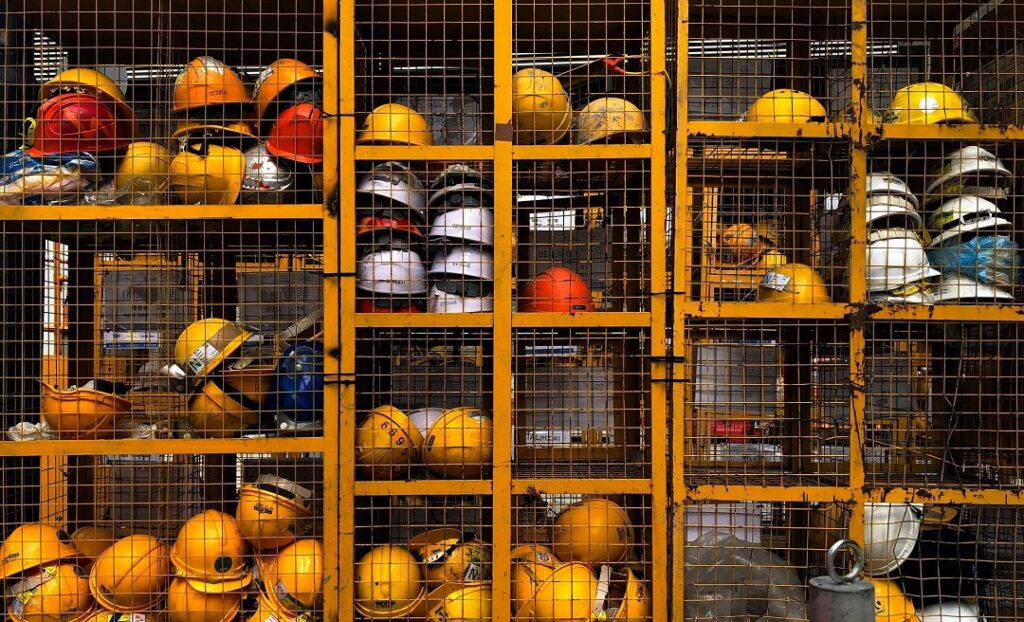 a rusty, yellow mesh locker filled with yellow construction helmets