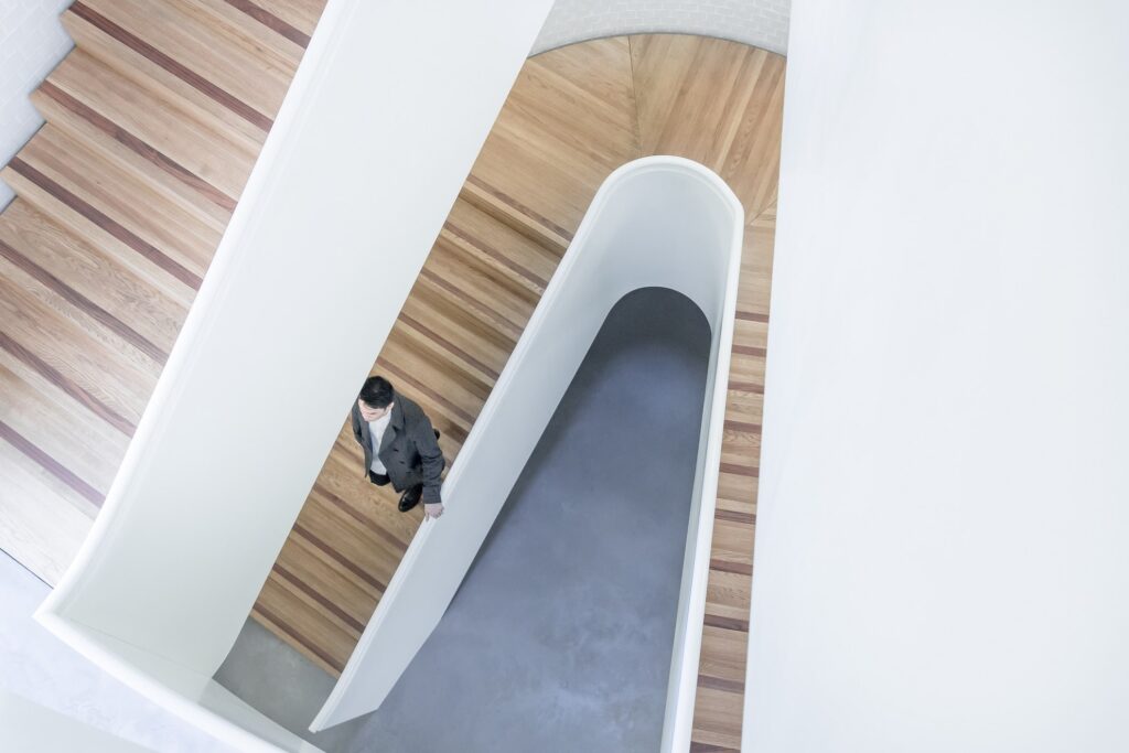 man walking down a wooden staircase in the newport street gallery in london