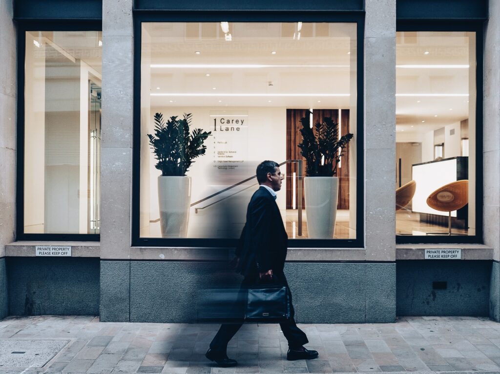 a man carrying a briefcase and walking past the front windows of carey lane in london