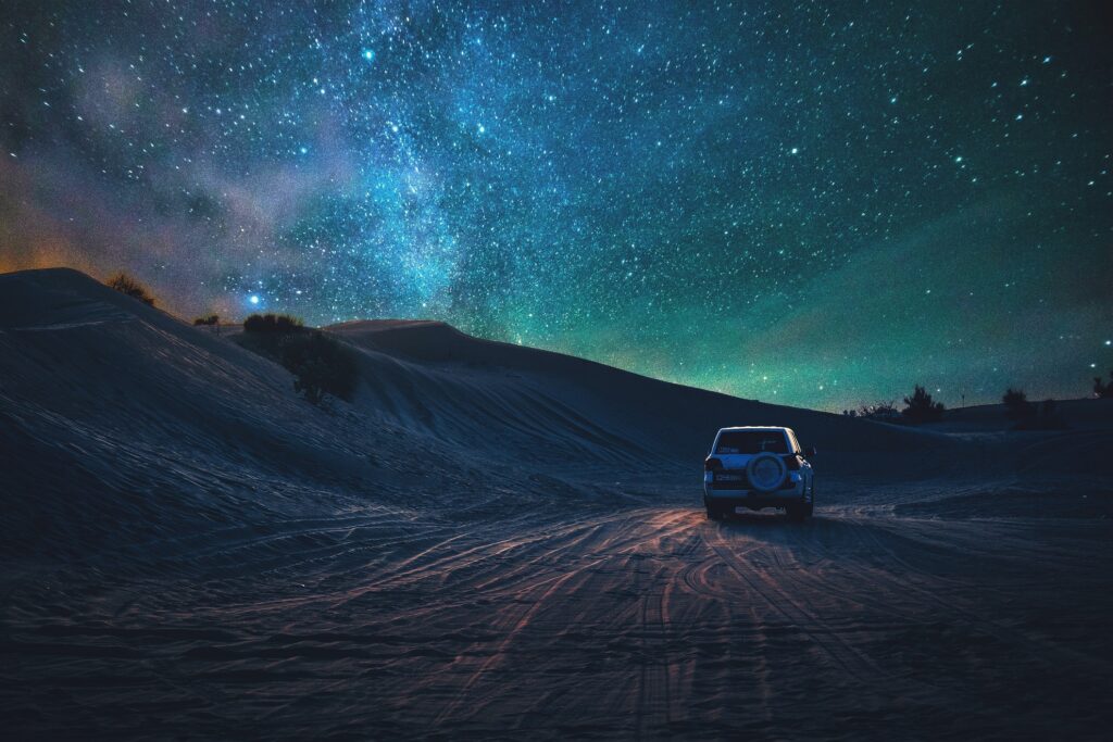 a car driving a desert terrain and under a starry night