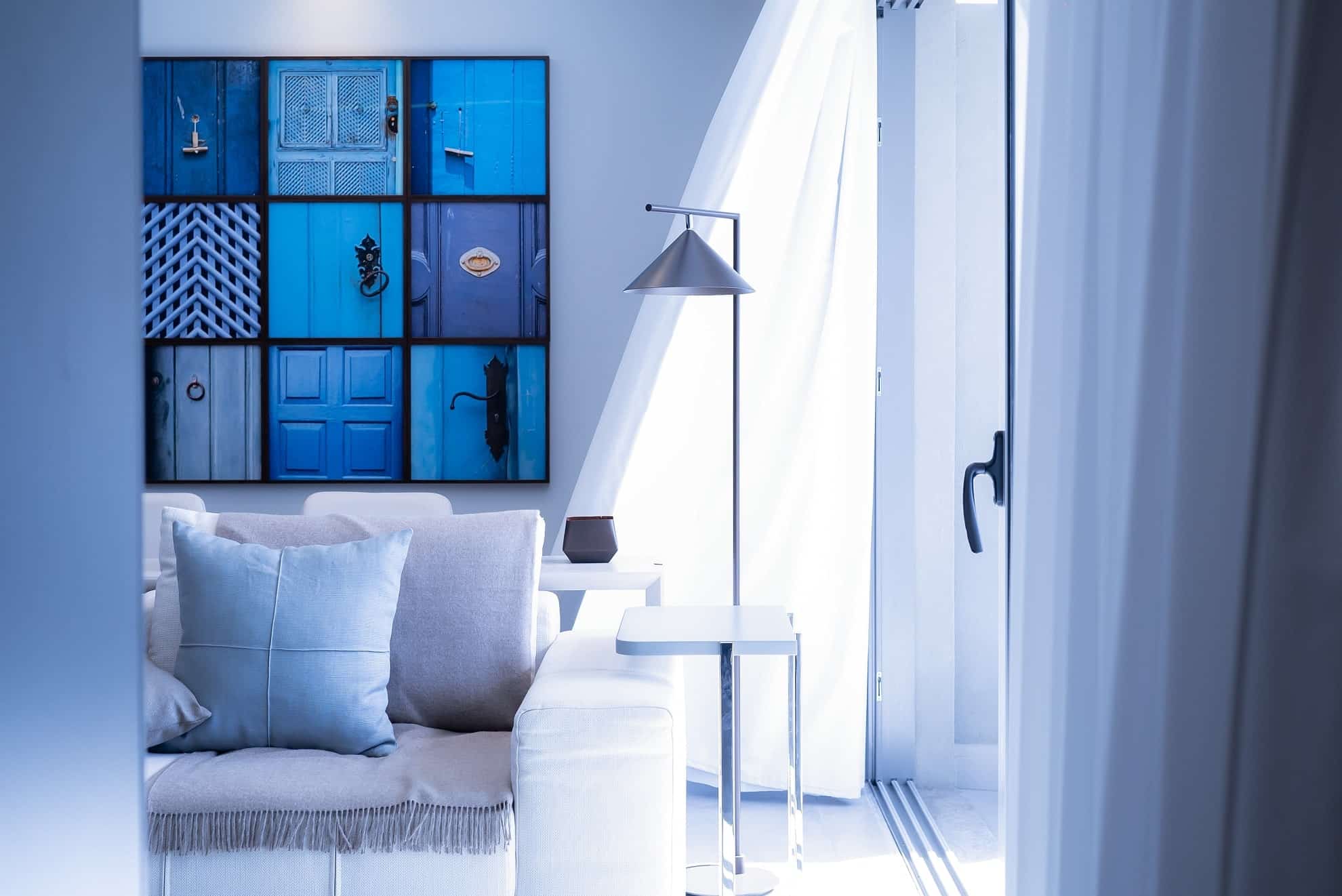 An apartment living room with blue, white, and silver furniture, curtains, and fixtures.