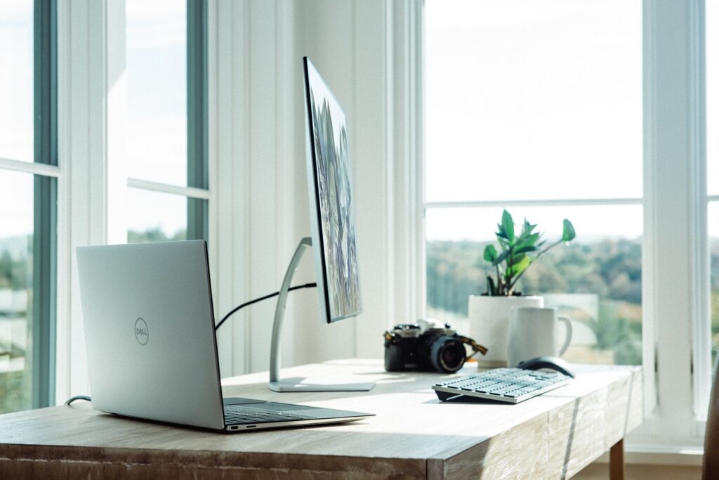 a silver laptop and desktop on top of a white wooden table