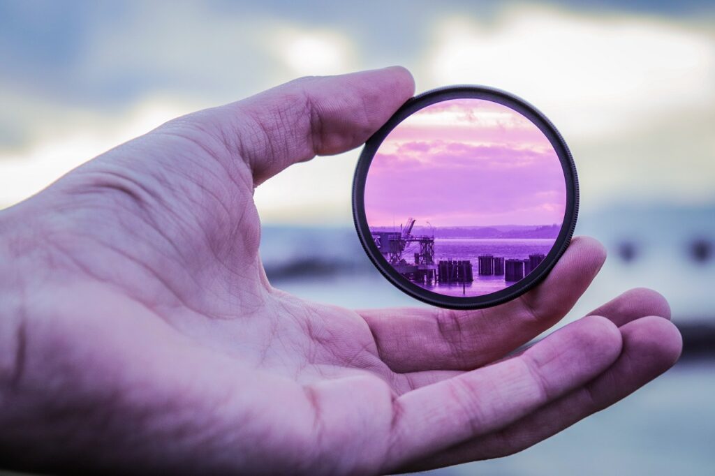 a person holding a lens to focus on structures on the water
