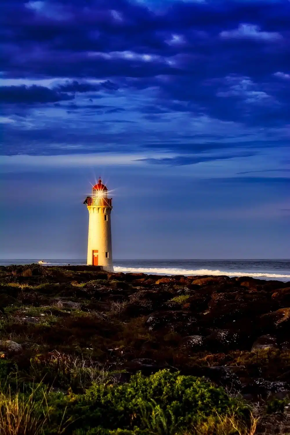 a lighthouse with its lamp turned on in an early evening