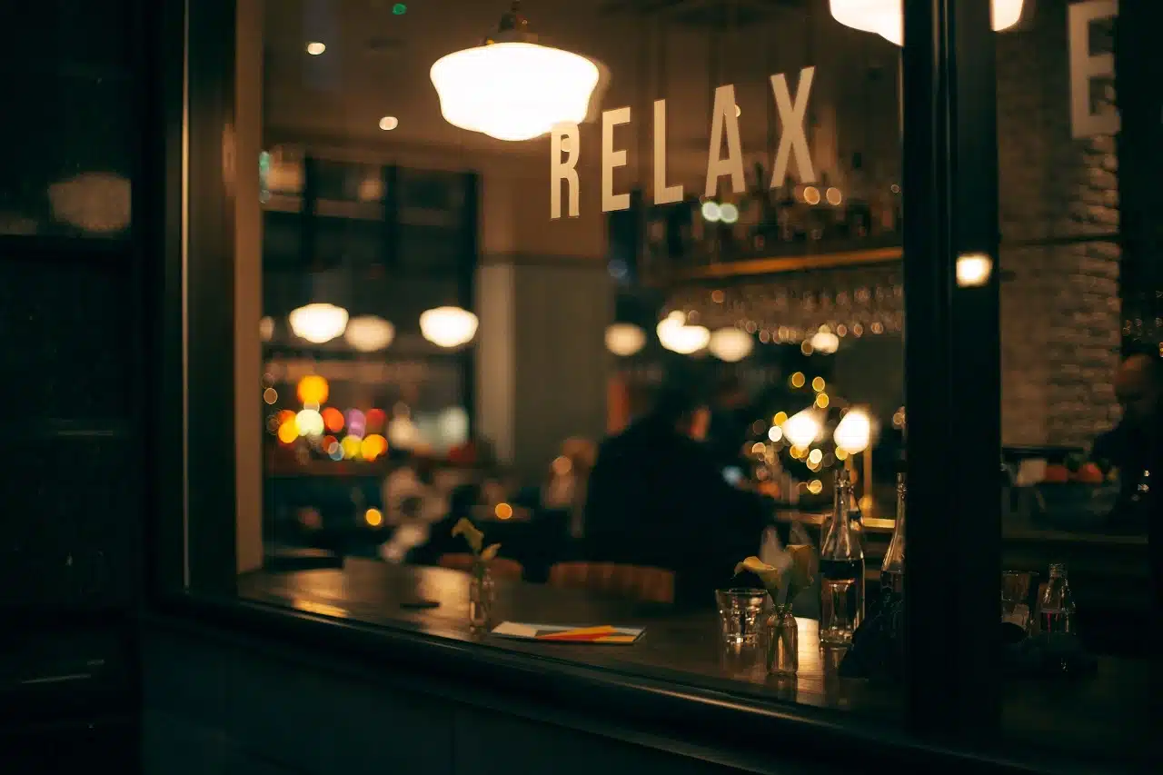 a restaurant window with the words 'relax' illuminated by evening lights