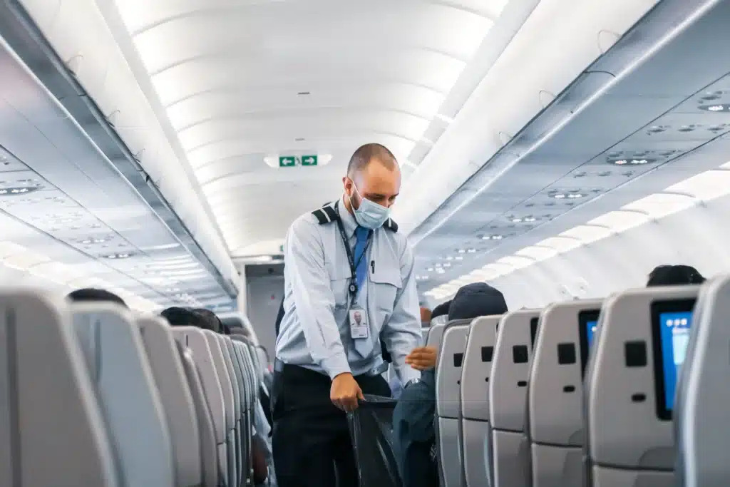 A male flight attendant walking the aisle of an airplane, representing the concept of tax deductions for fly in fly out employees.