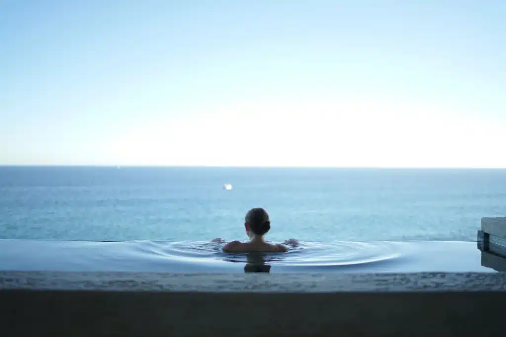 A woman at the edge of an infinity pool overlooking the open ocean, representing the concept of tax deductions for hospitality workers.