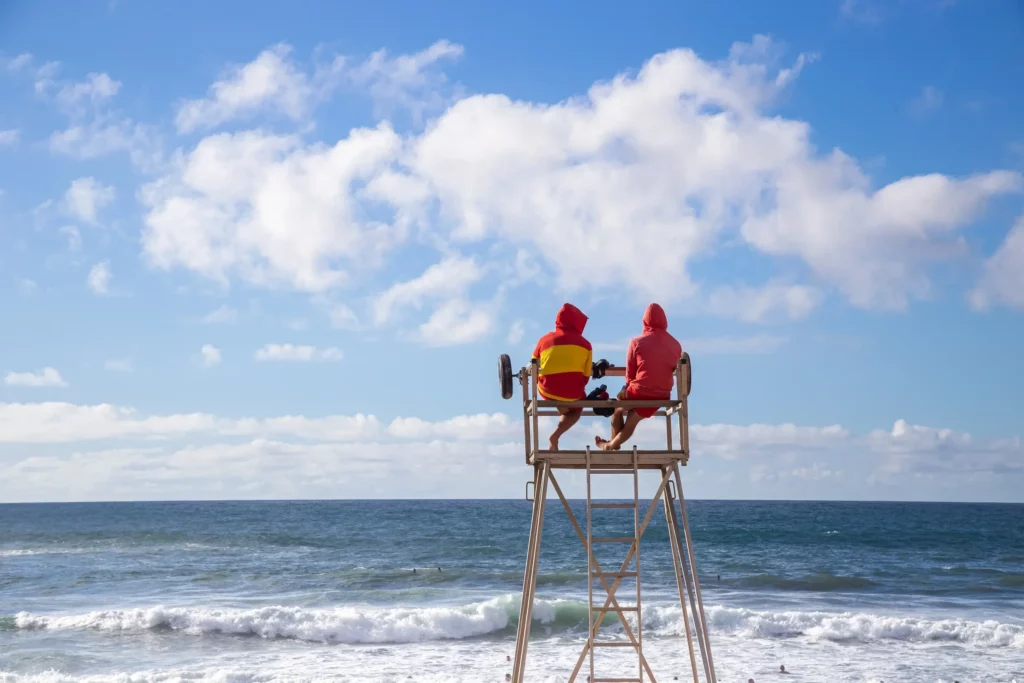 Two lifeguards watching people swimming at sea, representing the concept of tax deductions for lifeguards.