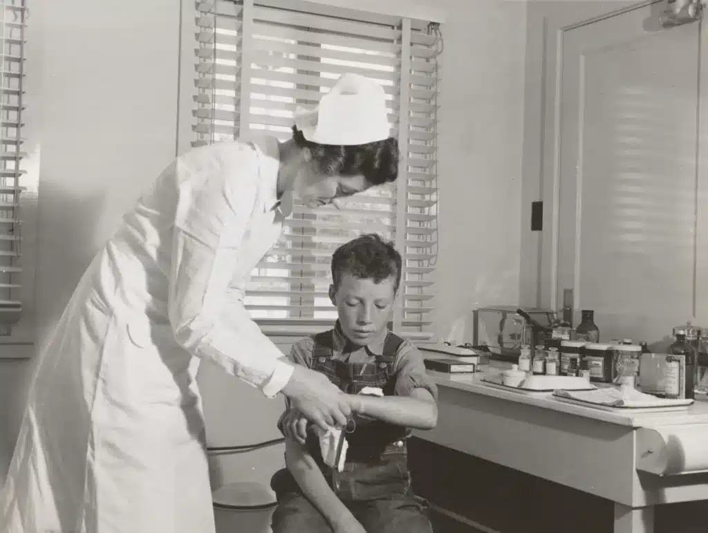 a vintage photo of a nurse placing a bandage on a boy's arm representing the concept of tax deductions for nurses
