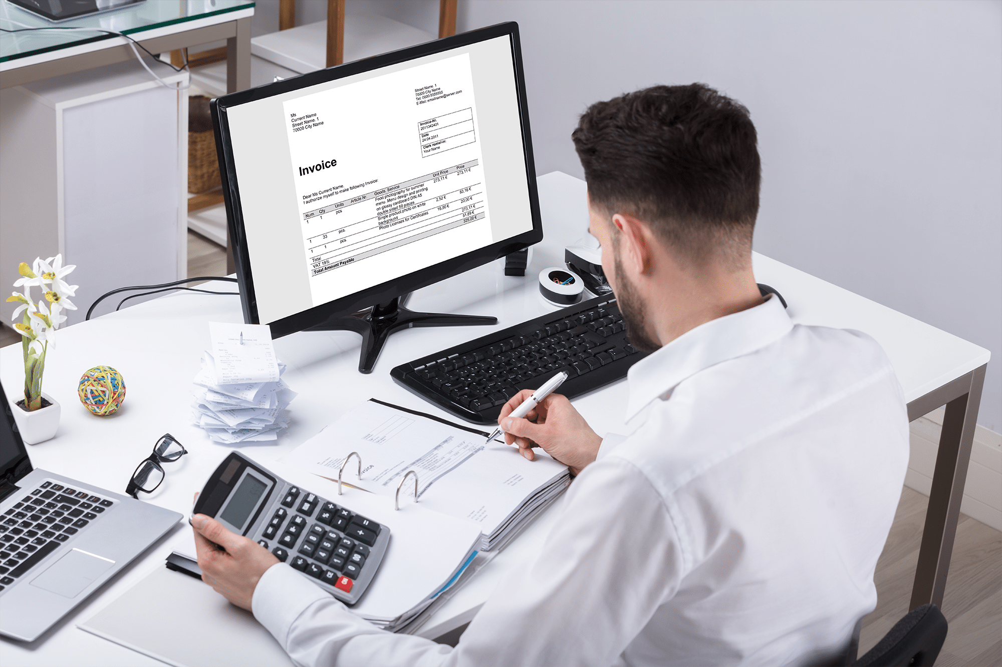 Young Businessman Calculating Tax With Calculator At Desk.