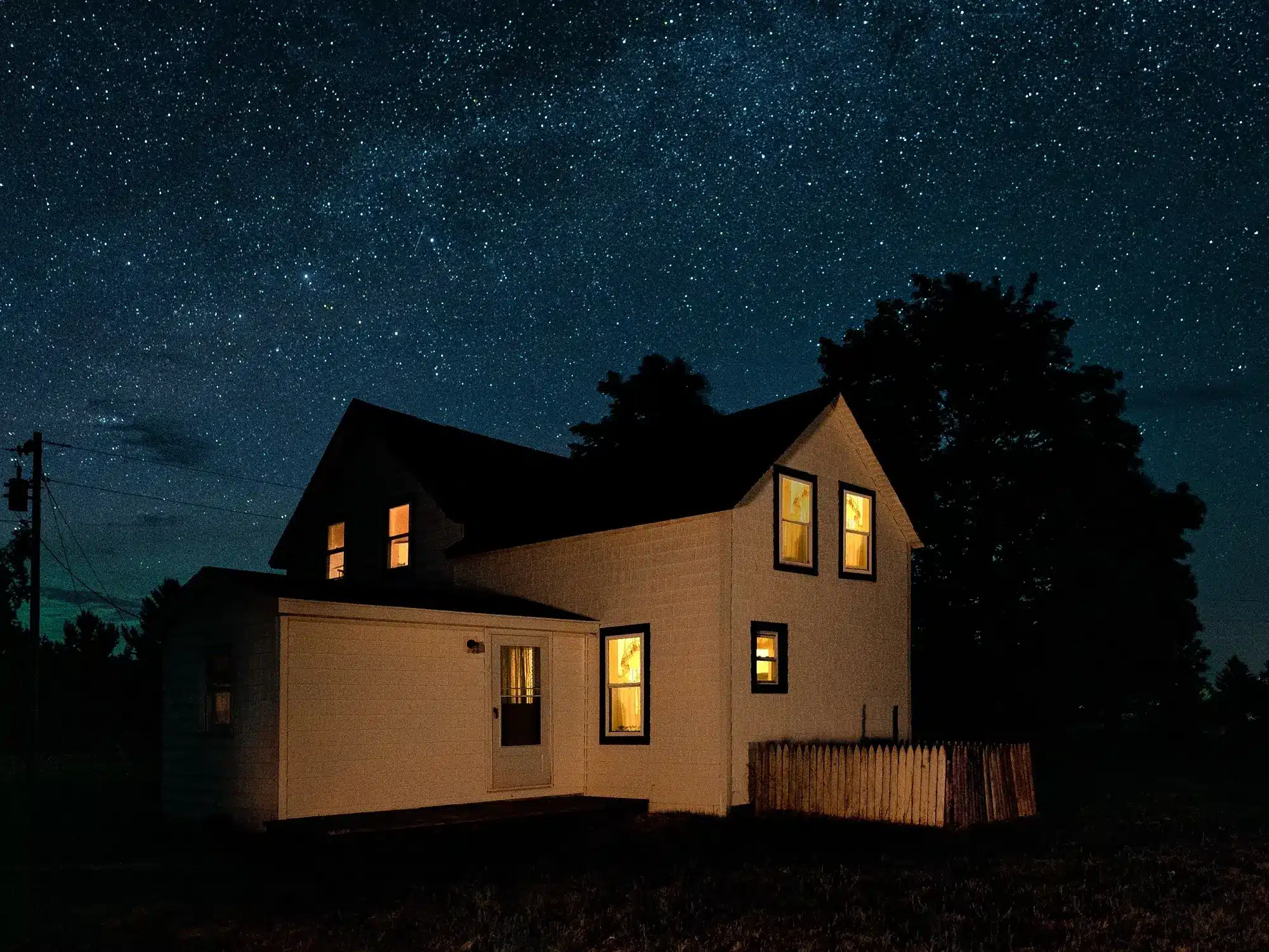 A wooden house illuminated by the night sky.