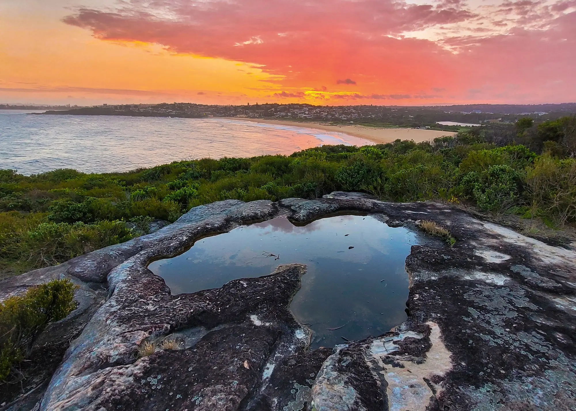 A large rock with a puddle of water in North Curl Curl Beach, NSW, Australia.