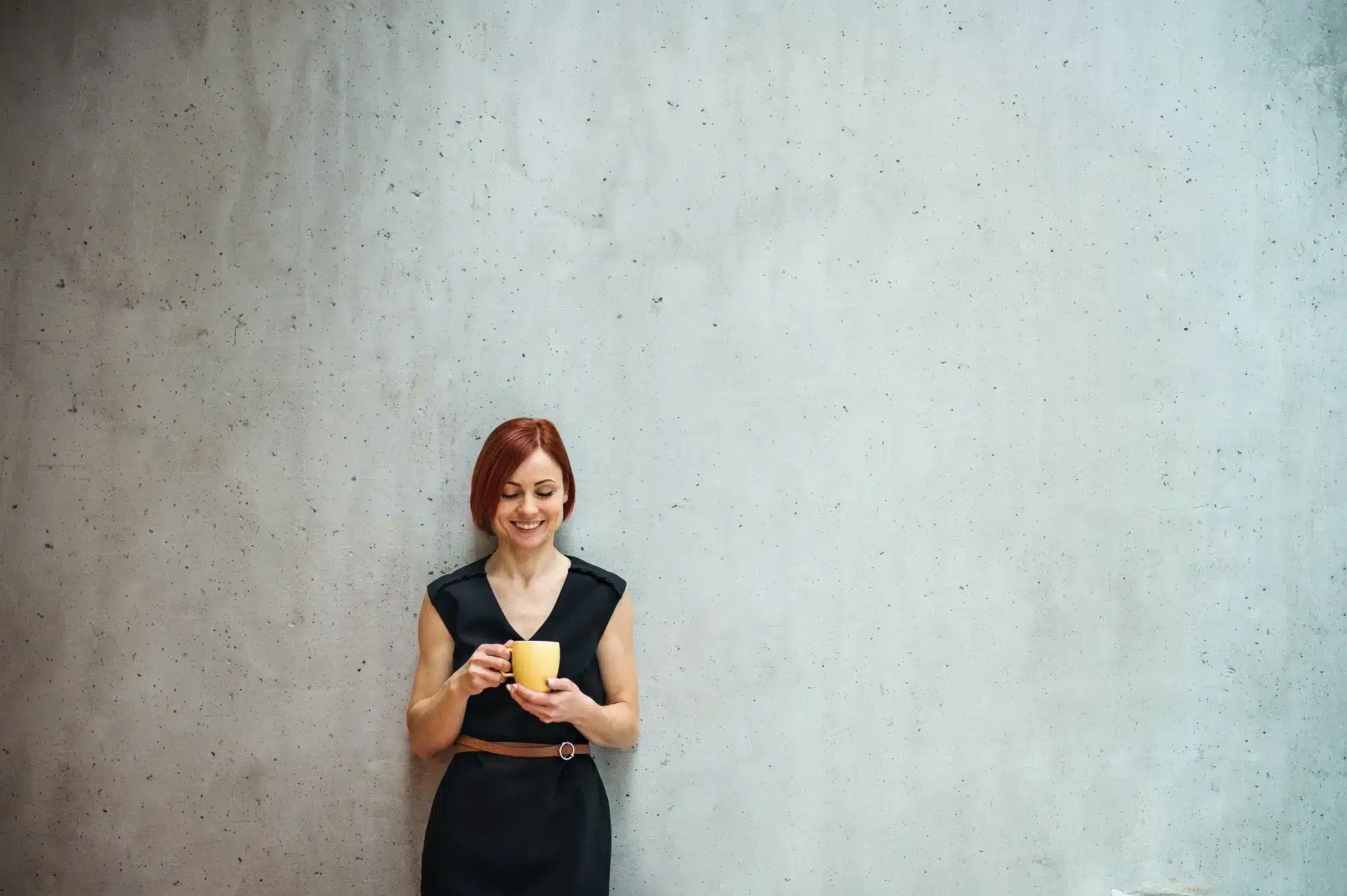 A woman leaning against a grey concrete wall, representing the concept of director penalty notice.