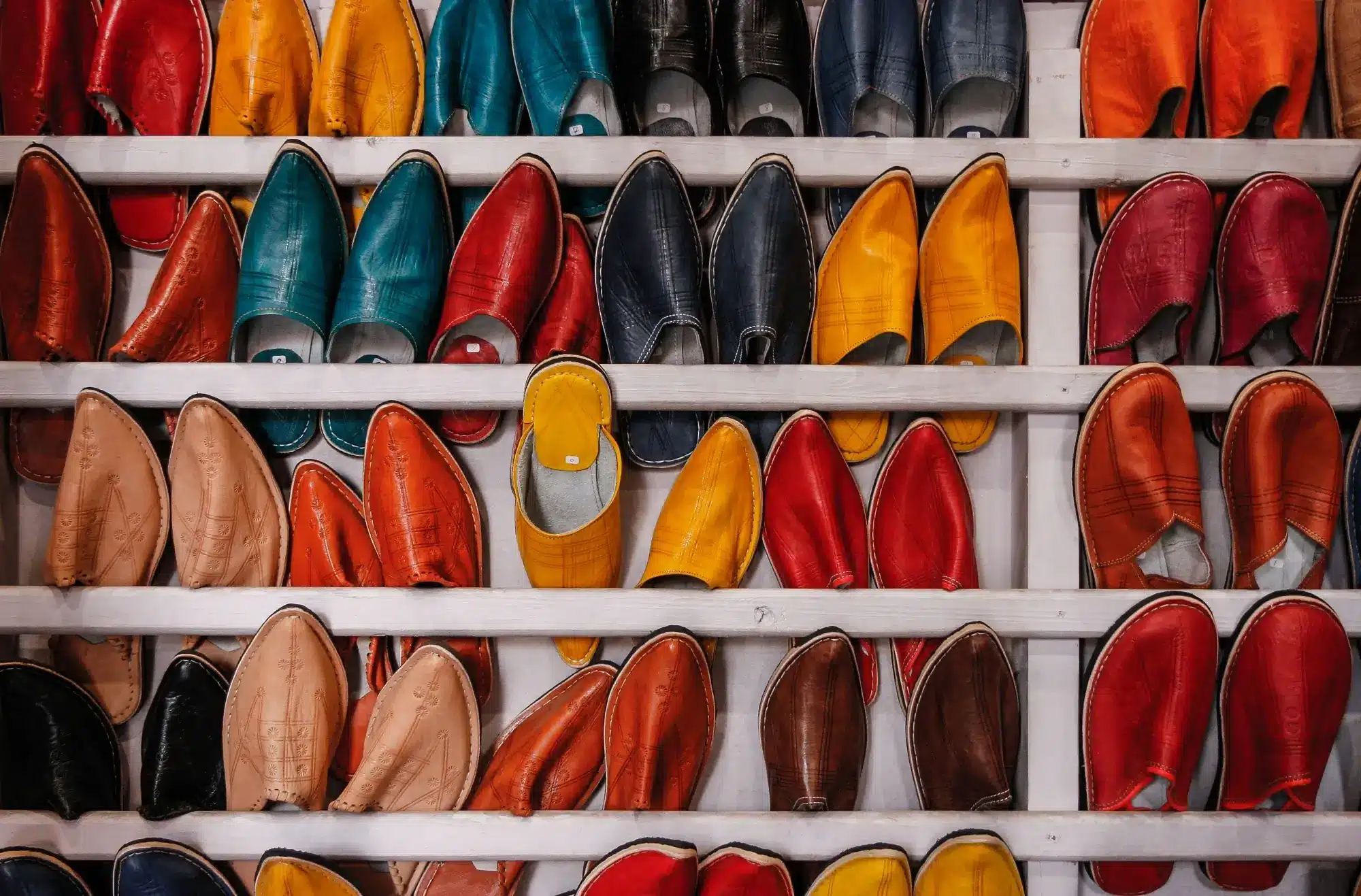 An assortment of shoes with different colours on a white shelf, representing the concept of GST financial supplies.