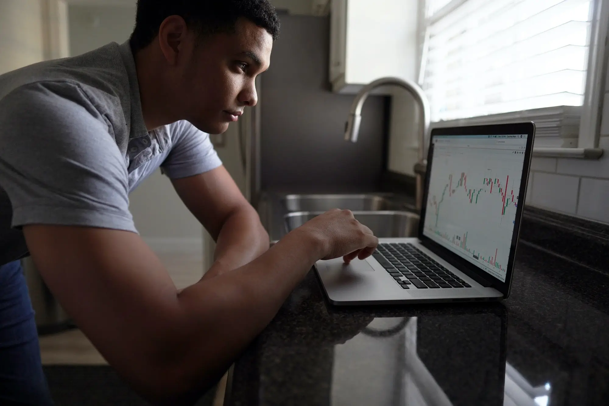 A man looking at stock charts on his laptop computer.