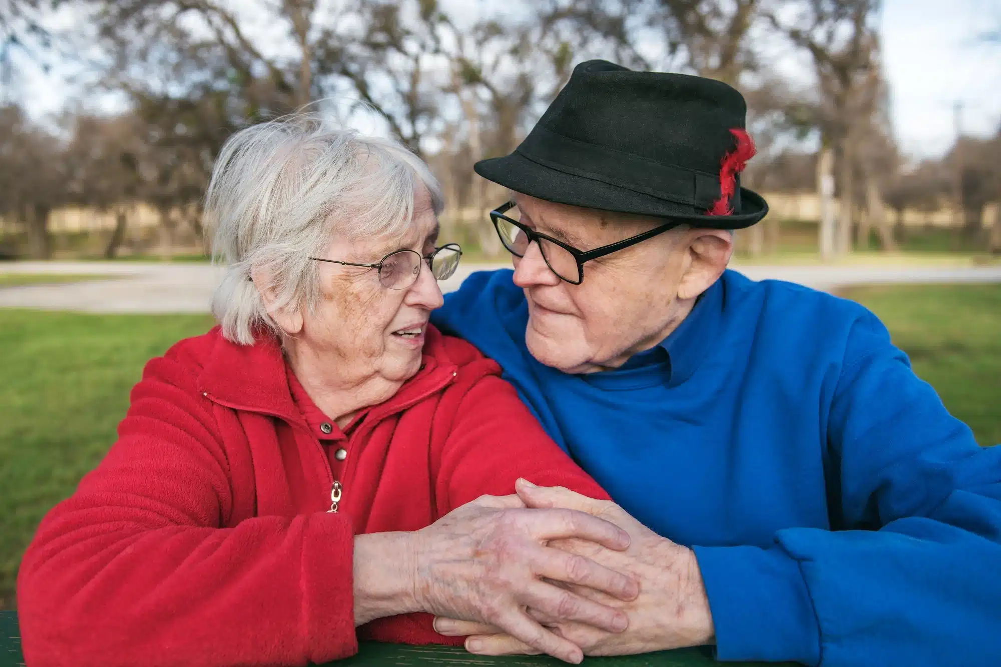 A retired couple looking at each other while holding hands.