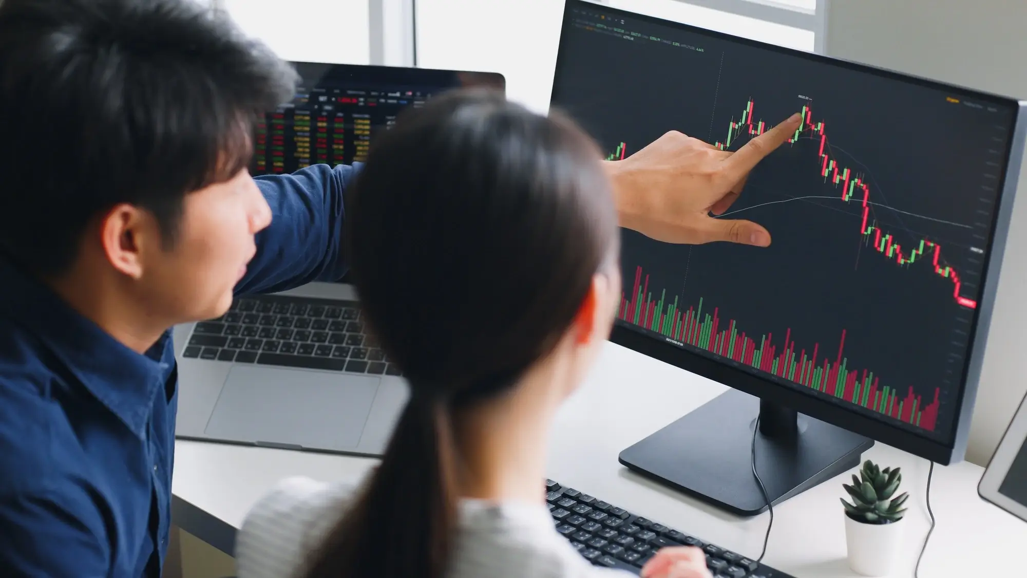 Investors discussing a stock chart on a computer, monitoring stock charts, representing what is stock trading.