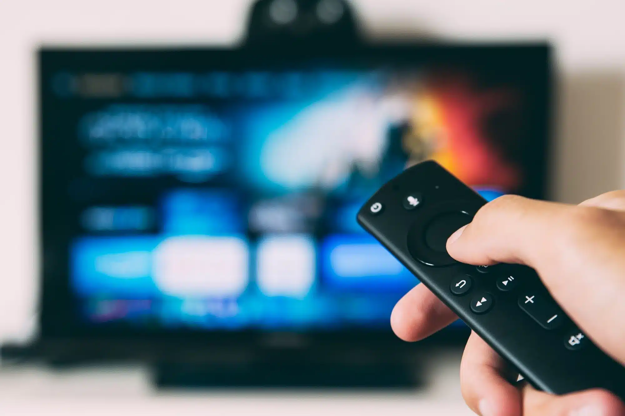 A person holding a remote while flicking through the movies on television, representing the concept of entertainment FBT.