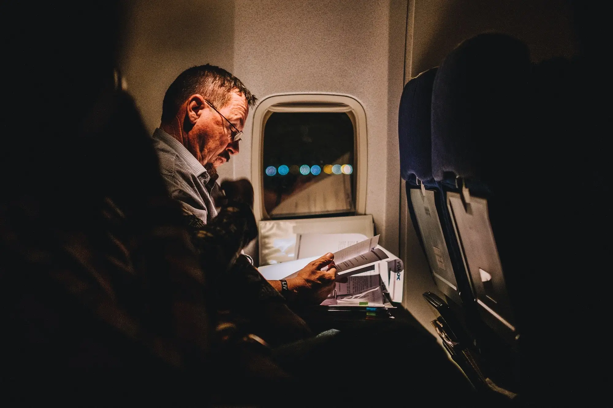 A man on a plane reading.