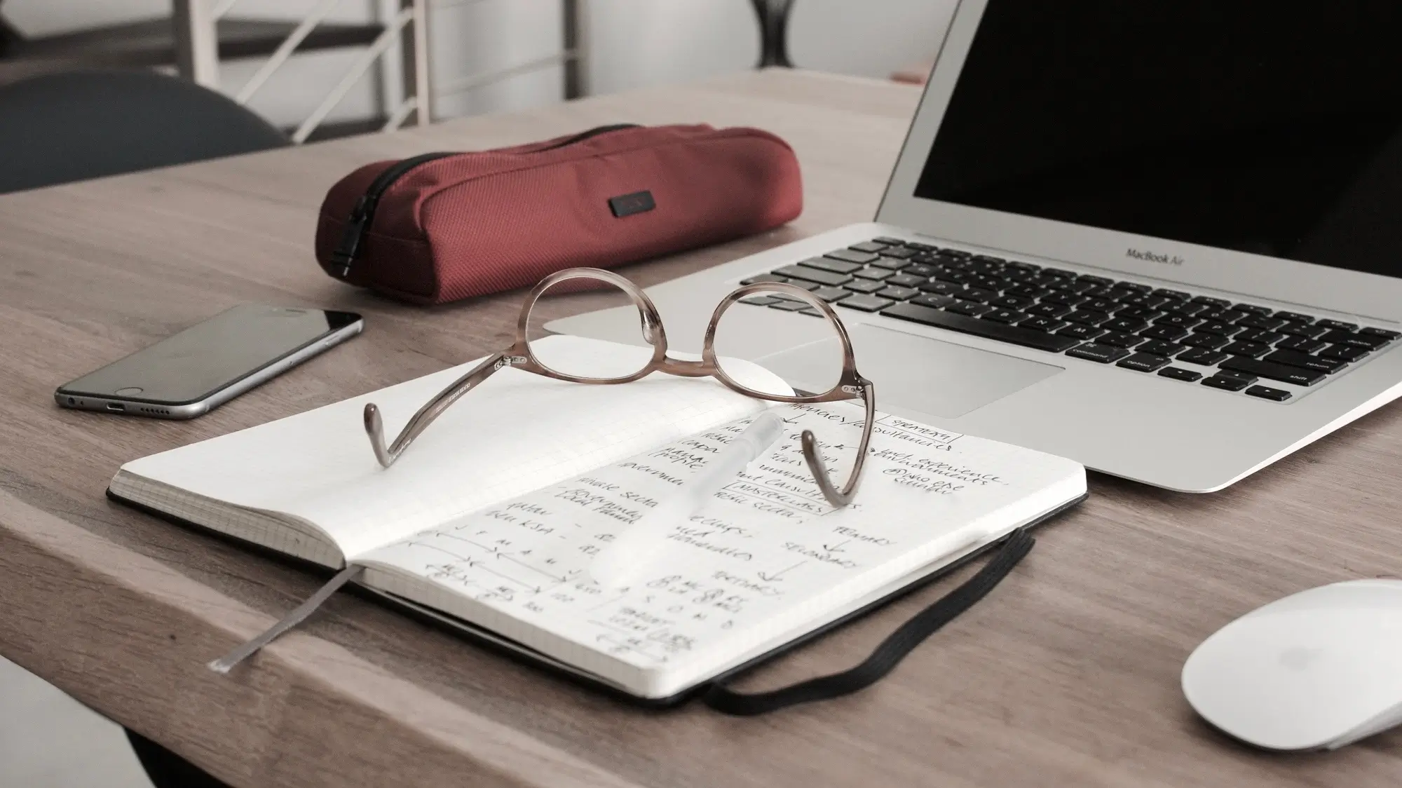 A laptop, a pair of glasses, and a notebook.
