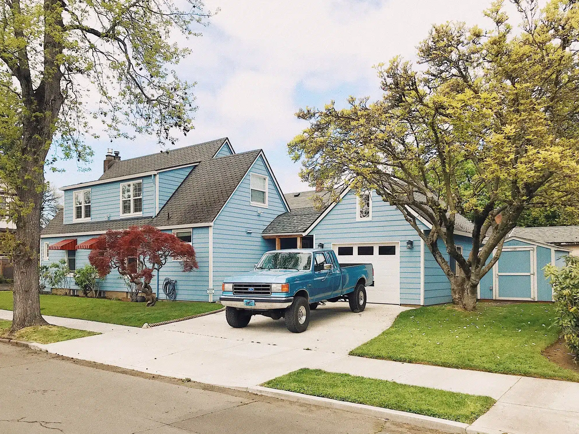 A suburban home with a vintage Ford pickup in its driveway, representing the concept of property fringe benefit.