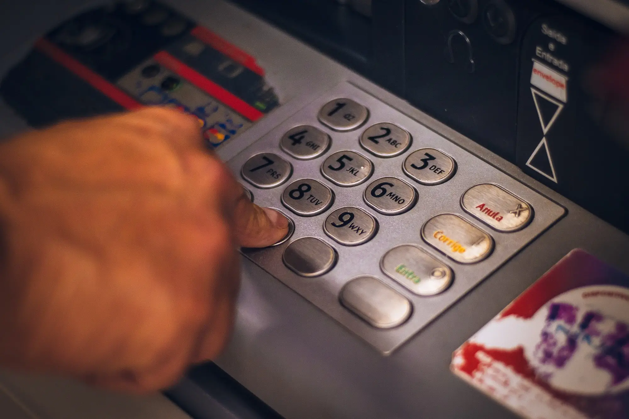 A hand pressing the keys on an ATM.