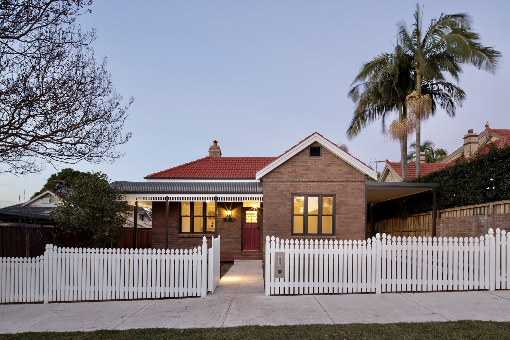 A house with a white picket fence at dusk, representing the concept of first home super saver scheme.
