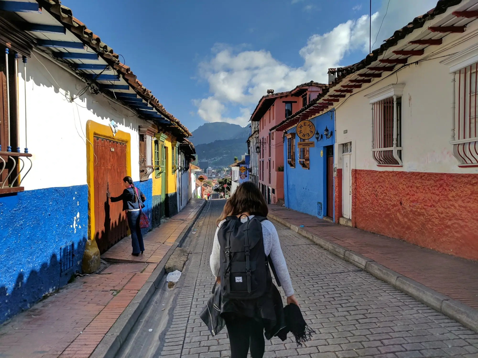 A woman walking past houses with colourful paints.