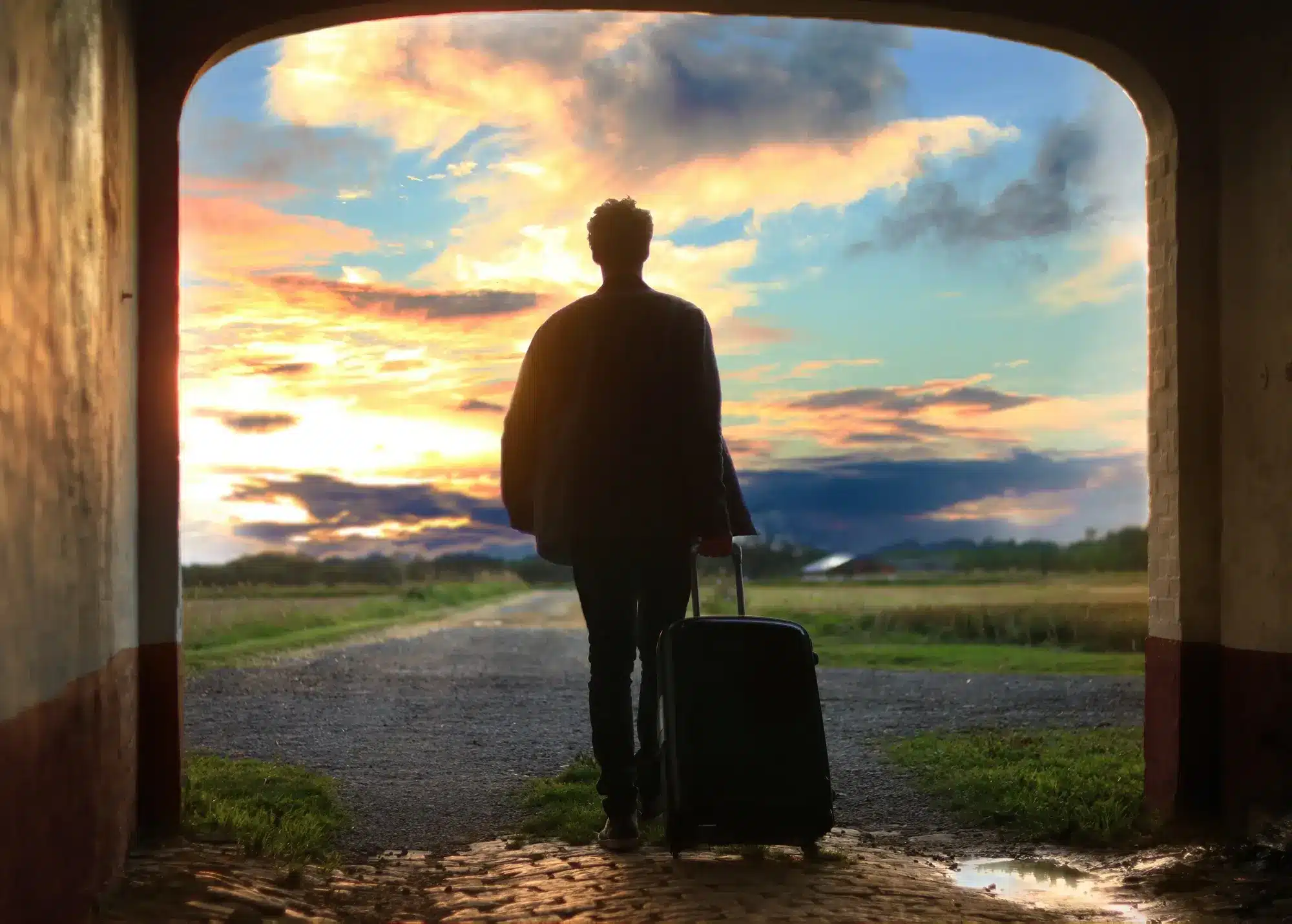 A man pulling a luggage through a tunnel that exits into a scenic view, representing the concept of working holiday maker.